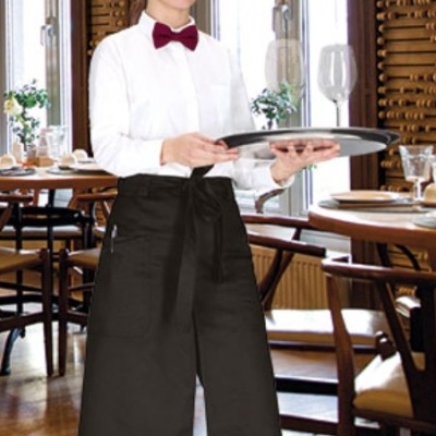 Garçonete com camisa branca, gravata borboleta vermelha e avental preto comprido num restaurante