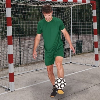 Homem a jogar futebol numa quadra com baliza de futsal