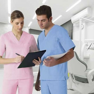 Dois profissionais de saúde com uniformes médicos rosa e azul em consultório dentário