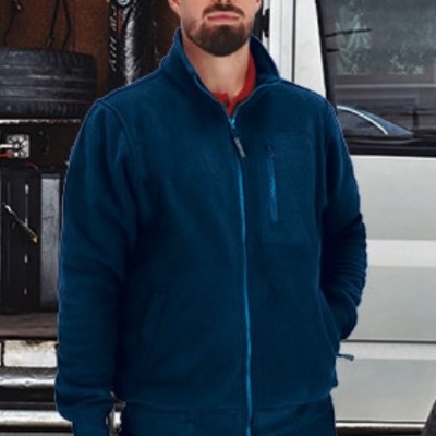 Homem com casaco polar azul escuro segurando caixa de ferramentas preta com tampa amarela em frente a carrinha branca