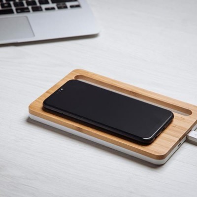 Carregador sem fios em madeira clara com telemóvel preto