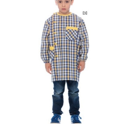 Menino com bata xadrez azul e amarelo, calças jeans e ténis azuis em fundo branco.