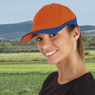 Mulher sorridente a usar boné laranja com aba azul no campo