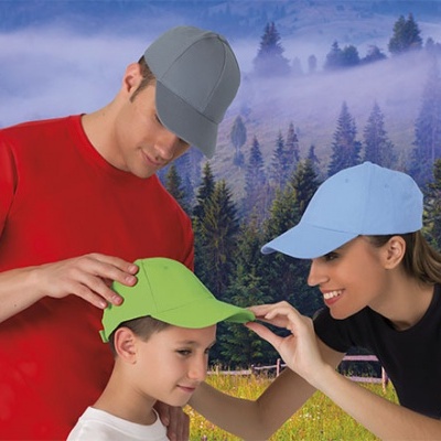 Três pessoas com t-shirts e bonés coloridos num ambiente natural com árvores e névoa