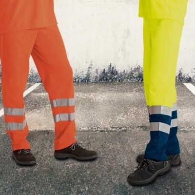 Pessoas vestindo pantalonas de trabalho com faixas refletoras em estacionamento