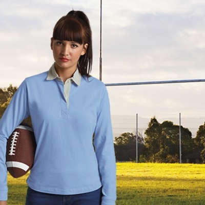 Mulher com polo azul segurando bola de futebol americano em campo de rugby