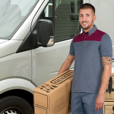 Homem com camisa polo cinza e bordô e calças cinza ao lado de caixas VALENTO DOUGH e carrinha branca