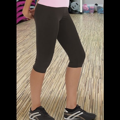 Calças justas desportivas pretas até ao meio da perna com ténis pretos e brancos num ginásio.