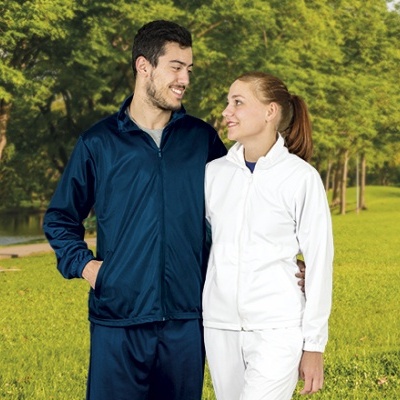 Casal em fatos de treino azul escuro e branco ao ar livre com árvores e relva