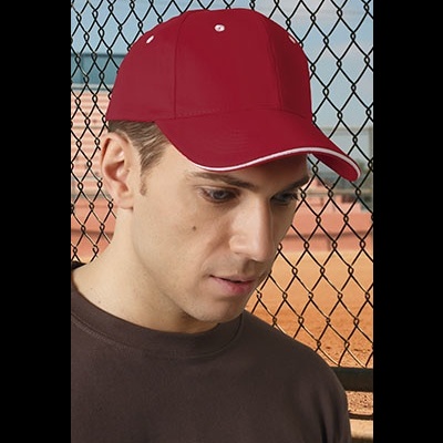 Boné desportivo vermelho com orifícios de ventilação brancos usado por homem junto a cerca de metal preta