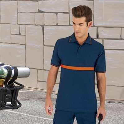 Homem com polo azul escuro e faixa laranja ao peito em rua com parede cinzenta