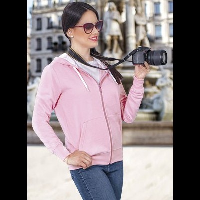 Mulher com casaco rosa e óculos de sol segurando câmara preta ao ar livre