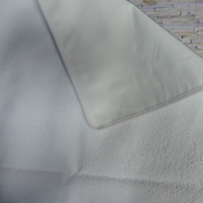 toalha branca de tecido felpudo e tecido macio pendurada com parede de pedra ao fundo