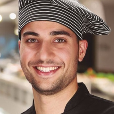 Chefe de cozinha com chapéu preto listrado e uniforme preto.