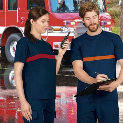 Duas pessoas de uniforme azul escuro com faixas coloridas, rádio emissor, clip-board e carro de bombeiros vermelho ao fundo.