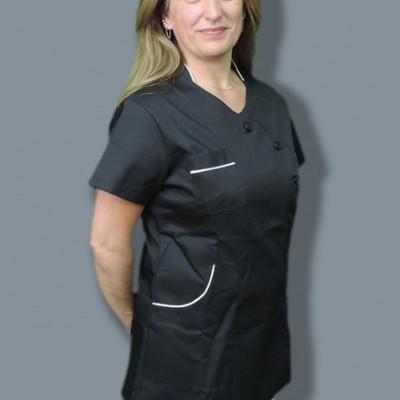 Mulher com bata preta de tecido liso e bolsos com detalhes brancos, calças brancas, fundo cinzento.