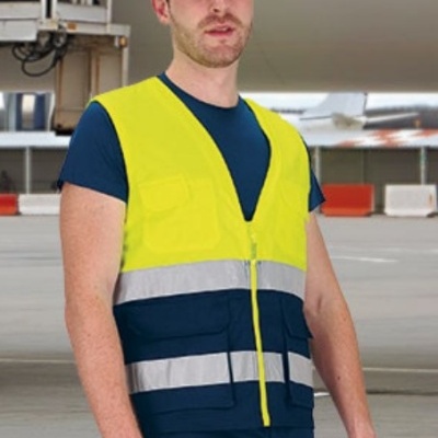 Homem com colete refletor amarelo e luvas de segurança num ambiente industrial