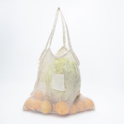 Saco de rede branco com frutos laranja visíveis