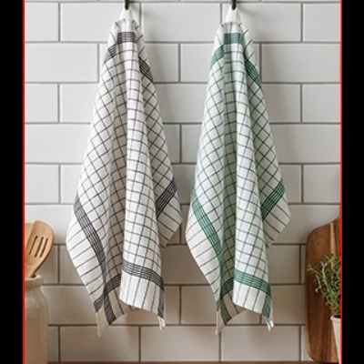 Duas toalhas de cozinha xadrez penduradas em ganchos numa parede de azulejos brancos