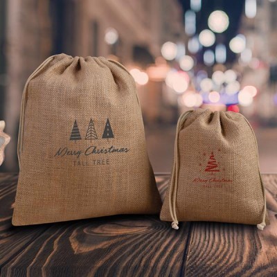 Dois sacos de juta com cordão, com desenhos e texto de Natal. 