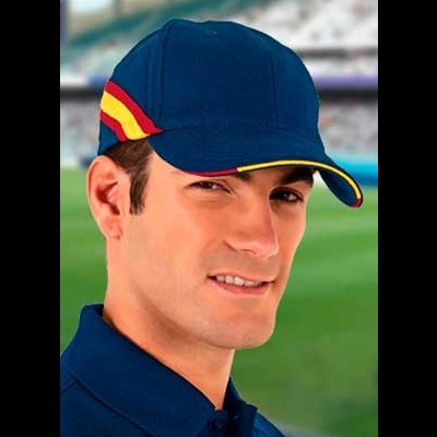 Homem com boné azul escuro com detalhes vermelho e amarelo em estádio desfocado