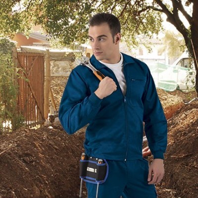 Homem com fato de trabalho azul e martelo ao ar livre junto a terra e vedação