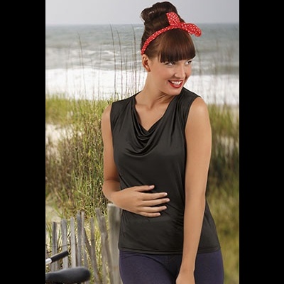 Mulher com blusa preta sem mangas e faixa vermelha com bolinhas no cabelo, em ambiente de praia