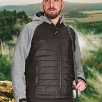 Homem com casaco acolchoado preto e cinza com capuz e calças pretas em paisagem natural