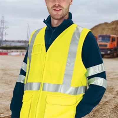 Homem com colete de segurança amarelo fluorescente e faixas refletoras em área de construção