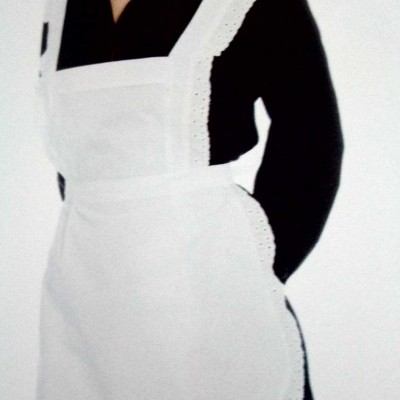 Mulher com avental branco rendado sobre camisa preta em fundo branco