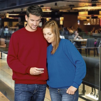 Dois jovens com camisolas vermelha e azul em ambiente interior moderno.