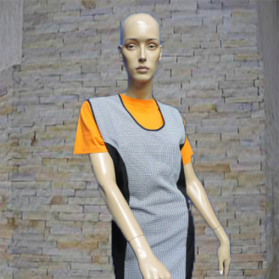 Vestido feitio avental xadrez preto branco sobre t-shirt laranja em manequim na parede de pedra