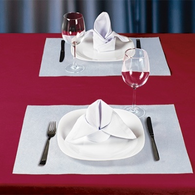 Mesa ajustada com toalha vermelha, pratos e guardanapos brancos, talheres pretos e copos de vinho