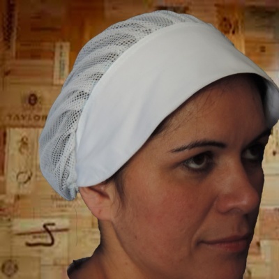 Touca de rede branca com faixa opaca usada por mulher em frente a parede com rótulos de vinho