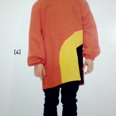 Criança com camisola laranja com detalhes amarelo e preto, calças e botas escuras, chapéu rosa em fundo branco