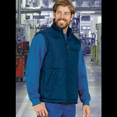 Homem com colete azul escuro acolchoado e camisa azul em ambiente industrial