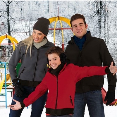 Três pessoas com casacos de inverno em parque infantil nevado