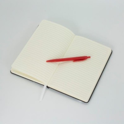 Caderno aberto com páginas de linhas cinzentas e caneta vermelha sobre superfície branca