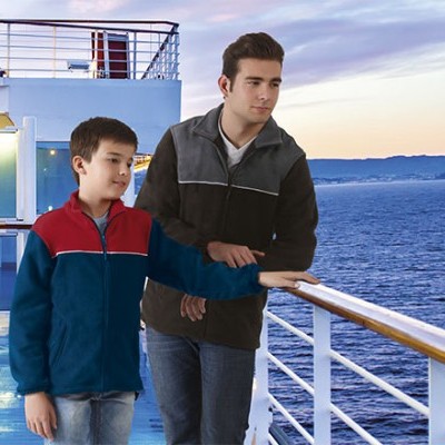 Dois rapazes no convés de um navio com casacos de inverno e mar ao fundo ao pôr do sol