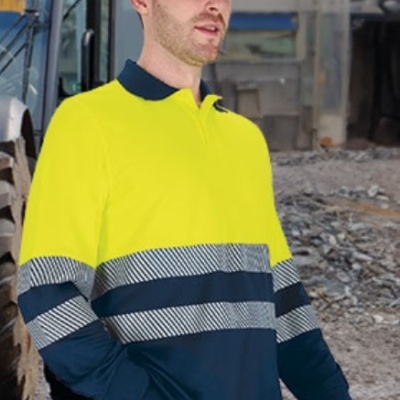 Homem com camisa de trabalho amarelo fluorescente e azul escuro com riscas refletoras e capacete azul em construção