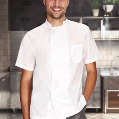 Homem com camisa branca de chef e calças listradas numa cozinha profissional moderna