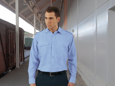 Homem a usar camisa azul clara de manga comprida numa estação ferroviária.