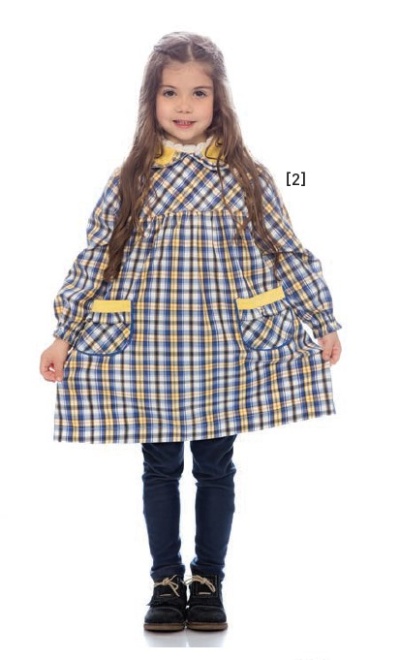 Menina com vestido de riscas quadradas azuis, brancas e amarelas, gola amarela e bolsos, calças azuis e sapatos pretos.