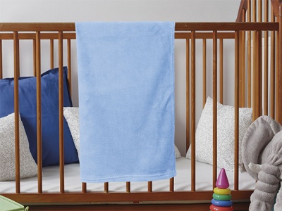 Berço de madeira com cobertor azul e almofadas dentro