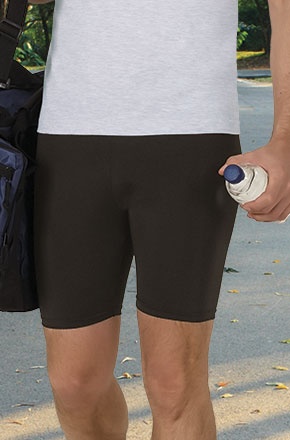 Pessoa com calções pretos justos e t-shirt branca segurando uma garrafa num ambiente exterior