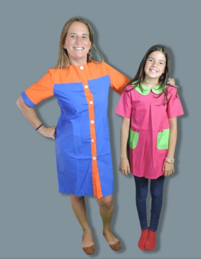 Mulher com vestido azul e laranja e criança com vestido rosa e verde em fundo cinzento