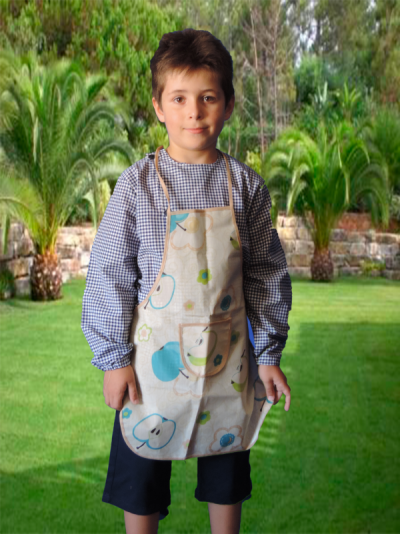 Menino com avental bege estampado com maçãs e flores, em relva com palmeiras ao fundo