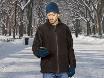 Homem com casaco preto felpudo e acessórios azuis numa rua de inverno com neve