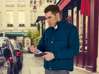 Homem com casaco acolchoado azul a usar máquina de pagamento na rua