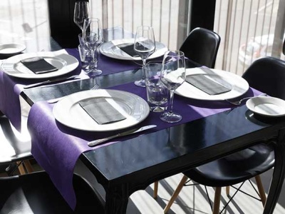 Mesa de jantar preta com caminho de mesa roxo e louça branca